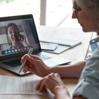 Old hr checking cv interviewing indian female job applicant by video call.