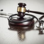 Gavel and Stethoscope on Reflective Wooden Table.