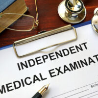 Independent Medical Examination (IME) form on a wooden table. Independent Medical Examination (IME) form on a wooden table.
