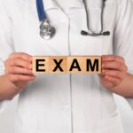 Word exam on wooden cubes in doctor hands. Medical checkup.