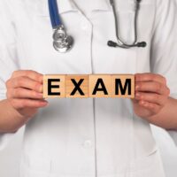 Word exam on wooden cubes in doctor hands. Medical checkup. Word exam on wooden cubes in doctor hands. Medical checkup.